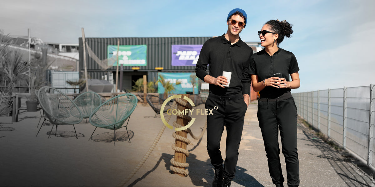 Twee personen in zwarte COMFY FLEX werkkleding met drankjes tijdens een pauze in de buitenlucht.